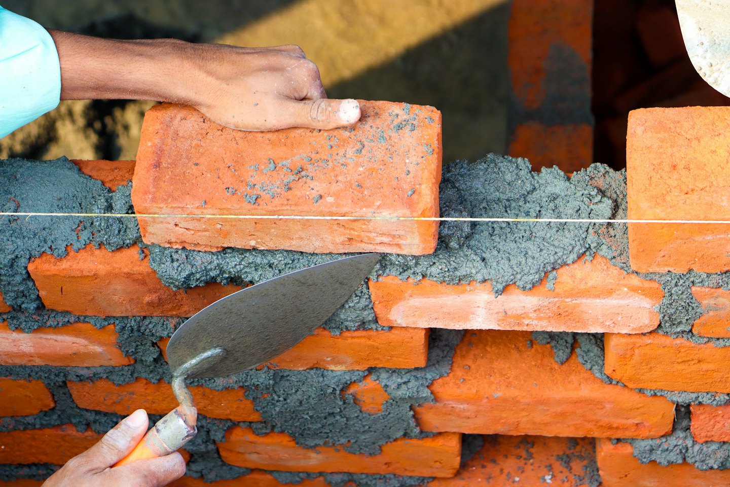Construction worker laying bricks with a trowel.